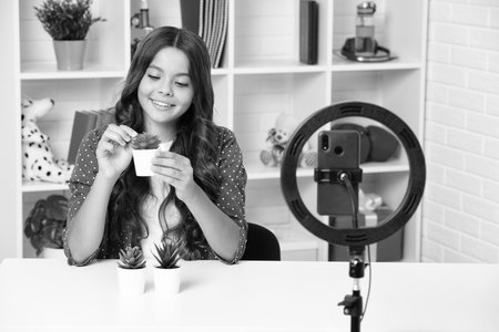 Teenager recording online media video. Teen girl streaming online and sharing social media content by mobile phone app network. Happy girl face, positive and smiling emotions.の写真素材