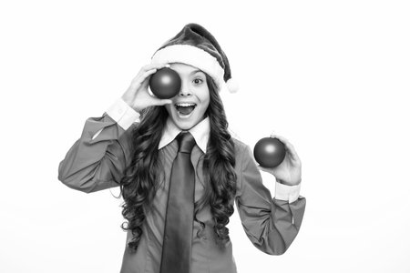 Funny face with christmas ball eyes. Christmas kids, New Year celebration concept. Portrait a teenage girl child with blue santa hat, shirt and necktie isolated on white background.の写真素材