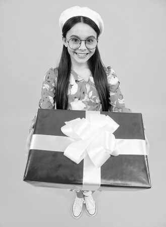 Teenager kid with present box. Teen girl giving birthday gift. Present, greeting and gifting concept. Happy teenager, positive and smiling emotions.の写真素材