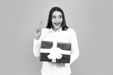 Attractive woman with present box posing with surprised face expression on gray background. Girl holding gift decorated with ribbon. Valentine day, birthday, happy new year gift people concept.の写真素材