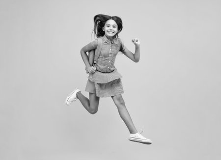 School teen girl in with backpack. Teenager student on isolated background. School leisure. Crazy run and jump. Kids learning, education, studying and knowledge.の写真素材