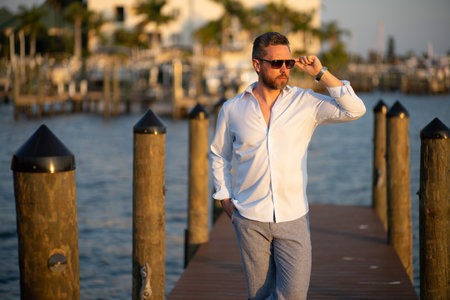 Portrait of handsome confident stylish man in yacht. Yacht club. Sexy man in fashion shirt posing on near yacht. Successful male model in the urban. Caucasian middle aged man near luxury yacht.の写真素材