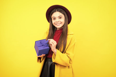 Happy teenager portrait. Child teen girl 12-14 years old with gift on isolated background. Birthday, holiday concept. Teenager hold present box. Smiling girl.の写真素材