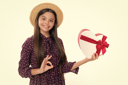 Summer kids sale. Portrait of happy smiling teenage child girl. Surprised teenage child holding gift box on white isolated background. Gift for kids birthday. Christmas or New Year present box.の写真素材