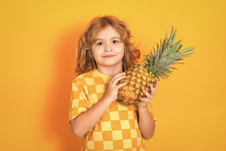 Kid with pineapple in studio. Studio portrait of cute child hold pineapple isolated on yellow background.の写真素材