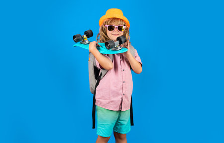 Photo of little child boy hold skateboard isolated on blue background. Casual culture. Child with skateboard and fashion stylish clothes in studio.の写真素材