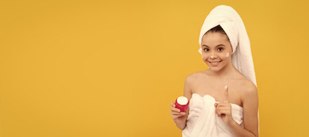 Kids facial treatment, cosmetology and spa, happy teen girl in shower towel apply facial cream. thumb up. Cosmetics and skin care for teenager child, poster design. Beauty kid girl banner.の写真素材