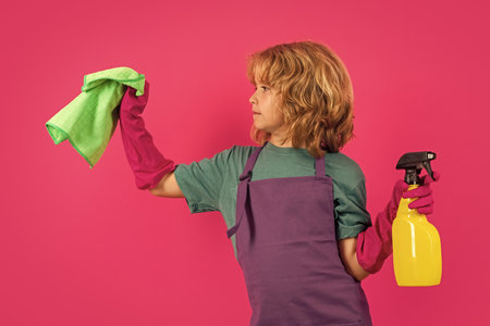 Little kid cleaning at home. Child doing housework having fun. Studio isoalted portrait of child housekeeper with wet flat mop on pink background.の写真素材