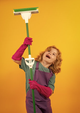 Children helping with housekeeping, cleaning the house. Housekeeping at home. Cute child boy helping with housekeeping on yellow studio backdround.の写真素材