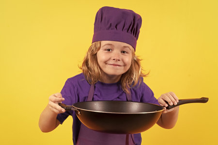 Kid cook with cooking pan. Portrait of little child in uniform of cook. Chef boy isolated on studio background. Cute child to be a chef. Child dressed as a chef hat.の写真素材