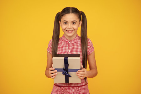 Emotional teenager child hold gift on birthday. Funny kid girl holding gift boxes celebrating happy New Year or Christmas. Happy teenager, positive and smiling emotions of teen girl.の写真素材