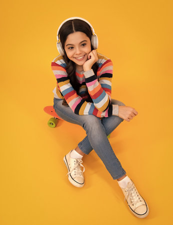Stylish teenage girl listening to music with headphones. Kids lifestyle concept. Wireless earphones. Urban kids style, stylish hipster teen.の写真素材