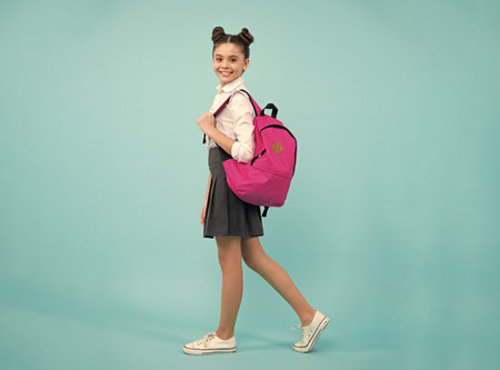 Schoolgirl in school uniform with school bag. Teenage girl student on blue isolated background. Learning knowledge and children education concept. Happy schoolgirl.の写真素材