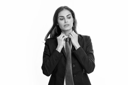 Business woman in suit and tie. Confident female entrepreneur. Businesswoman correct necktie, prepare for business meeting. Portrait of attractive elegant fixing suit isolated on white background.の写真素材