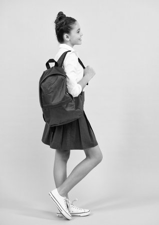 Schoolgirl in school uniform with school bag. Schoolchild, teen student on blue isolated background. Happy teenager, positive and smiling emotions of teen girl.の写真素材