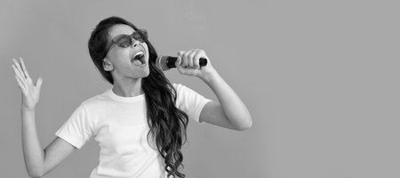 Happy kid singer sing karaoke song to microphone blue background, music. Horizontal poster of isolated child face, banner header, copy space.の写真素材