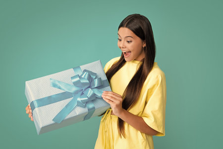 Surprised kids face. Teenager child with gift box. Present for holidays. Happy birthday, Valentines day, New Year or Christmas. Kid hold present box.の写真素材