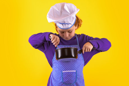 Kid chef cook with cooking pot stockpot. Portrait of little child in uniform of cook. Chef boy...