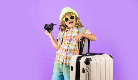 Child tourist with travel bag travelling. Kid with suitcase on studio isolated background.の写真素材