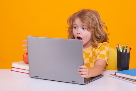 Excited school child using laptop computer. School child student learning in class, study english language at school. Elementary school child. Portrait of funny pupil learning.の写真素材