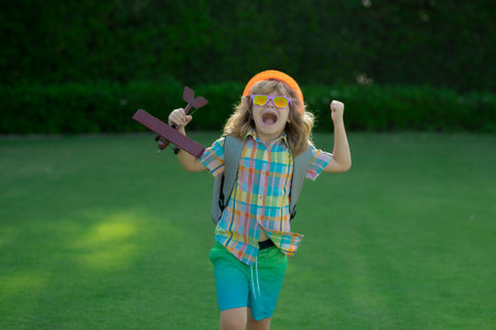 Boy kid dreams of becoming a pilot. Child playing with plane wings. Summer kids at countryside....
