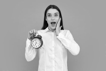 Surprised woman holding alarm watch. Isolated portrait.の写真素材