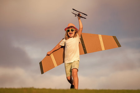 Dream of flying. Little children with toy airplane in a field at sunset. Success and child leader concept. Boy dreams of becoming a pilot.の写真素材