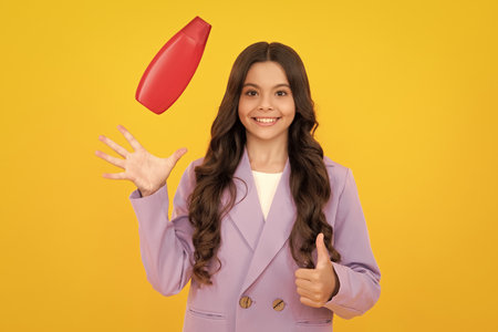 Child with shampoo conditioner. Daily cosmetic care. Teenager hold bottle of hair and skin care. Beauty health and cosmetics. Happy teenager, positive and smiling emotions of teen girl.の写真素材