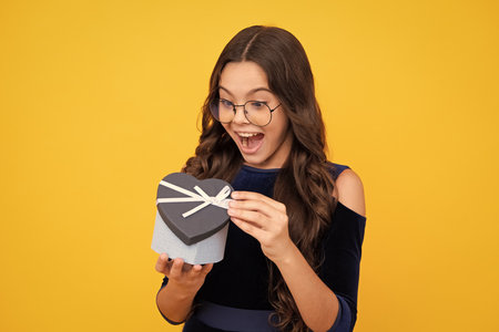 Excited teenager girl. Child teen girl 12-14 years old with gift. Birthday, holiday concept. Teenager hold present box. Amazed expression, cheerful and glad.の写真素材