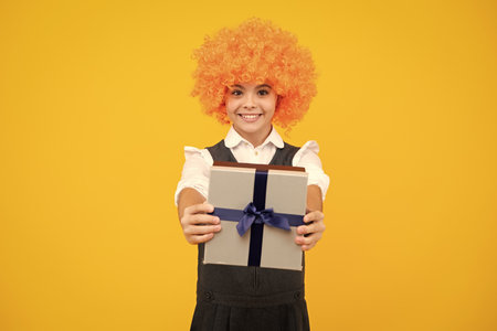 Cute teenager child girl congratulate with valentines day, giving romantic gift box. Present, greeting and gifting birthday concept. Funny child clown in wig and gift.の写真素材