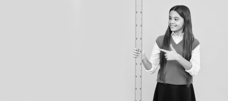 cheerful teen girl study math pointing finger on ruler measuring size, back to school. Portrait of schoolgirl student, studio banner header. School child face, copyspace.の写真素材