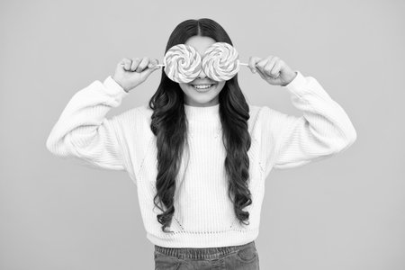 Teenage girl with lollipop, child eating sugar lollipops, kids sweets candy shop. Excited teenager girl. Happy face, positive and smiling emotions of teenager girl.の写真素材