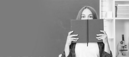teen girl in high school behind workbook at blackboard. Portrait of schoolgirl student, studio...