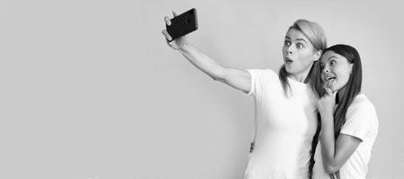 Mother and daughter kid banner, copy space, isolated background. family portrait of happy mother woman and child girl making selfie on smartphone.の写真素材