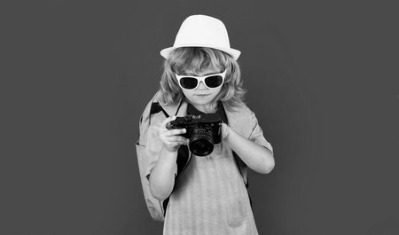 Child traveller photographer with camera taking pictures in studio. Kid photo camera. Lifestyle...