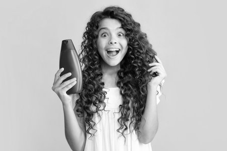 Teenage girl with shampoos conditioners or shower gel. Kids hair care cosmetic product, shampoo bottle. Excited teenager, glad amazed and overjoyed emotions.の写真素材