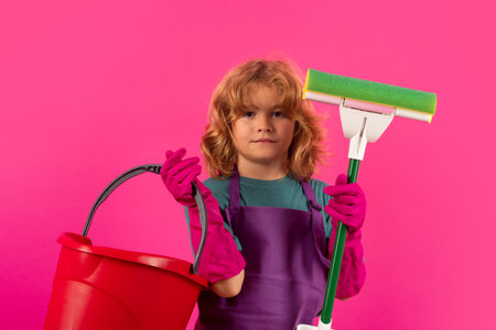 Kid helping with housework, cleaning. Housekeeping and home cleaning concept. Child use duster and gloves for cleaning. Studio isolated background.の写真素材