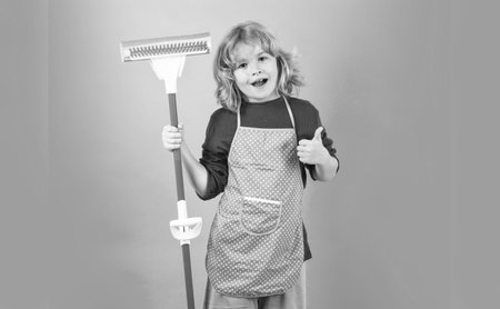 Child doing housework. Child use duster and gloves for cleaning. Funny child mopping house. Cleaning accessory, cleaning supplies. Housekeeping and home cleaning.の写真素材