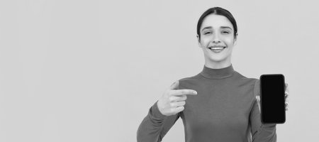 Woman isolated face portrait, banner with copy space. smiling lady pointing finger on smartphone, look here.の写真素材