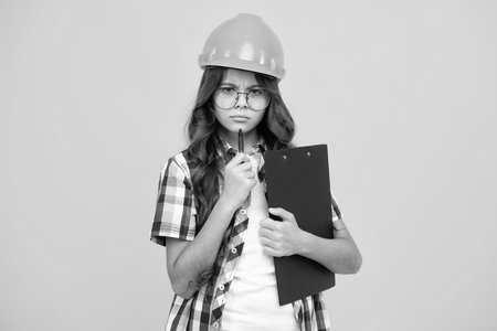 Teenager child painter in helmet with clipboard. Child in hard hat. Kid engineer on construction site. Renovation and repair.の写真素材