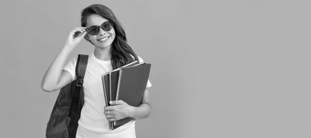happy kid with backpack and copybook in sunglasses ready to study at school, school. Banner of schoolgirl student. School child pupil portrait with copy space.の写真素材