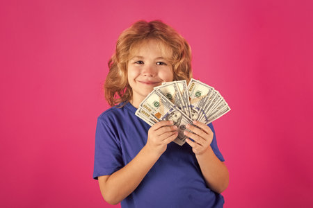 Money win, big luck. Kid having a lot of hundred dollars isolated on studio background.の写真素材