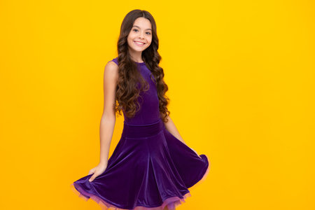 Happy girl face, positive and smiling emotions. Teenager child girl wearing ball dress on yellow isolated background.の写真素材