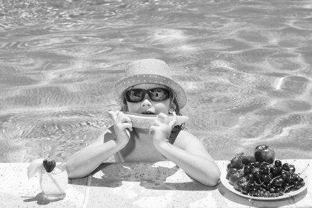 Happy child playing in swimming pool. Summer kids vacation. Summer fruit for children. Little kid...