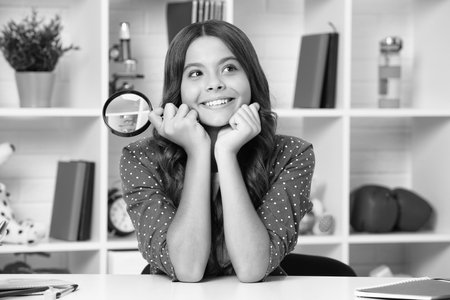 Teen school girl with magnifying glass, knowledge. Happy schoolgirl, positive and smiling emotions.の写真素材