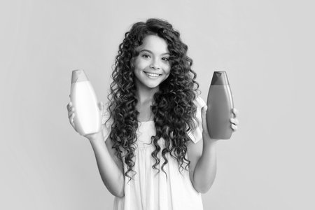 Happy teenager, portrait of child girl with bottle shampoo conditioners or shower gel. Kids hair care. Hair cosmetic product, shampoo bottle. Smiling girl.の写真素材