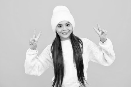 Teenager child 12, 13 ,14 years old showing fingers victory sign. Number two, v-sign symbol isolated on yellow background.の写真素材