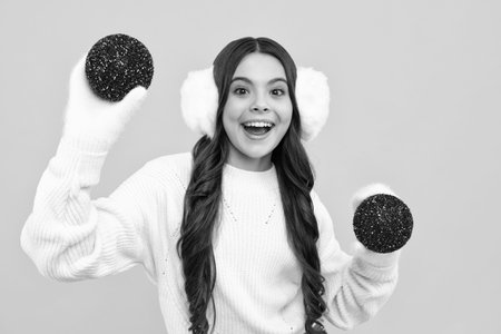 Teenager child santa girl in fur sweater, christmas ball isolated on yellow background. Happy New Year, celebration holiday concept.の写真素材