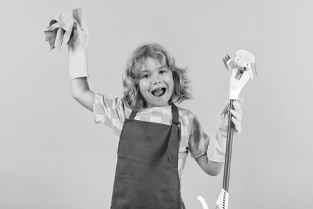 Child helping to clean. Child doing housework having fun. Studio isoalted portrait of child housekeeper with wet flat mop on yellow background.の写真素材