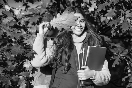 happy child hold notebook on autumn leaves backgroundの写真素材